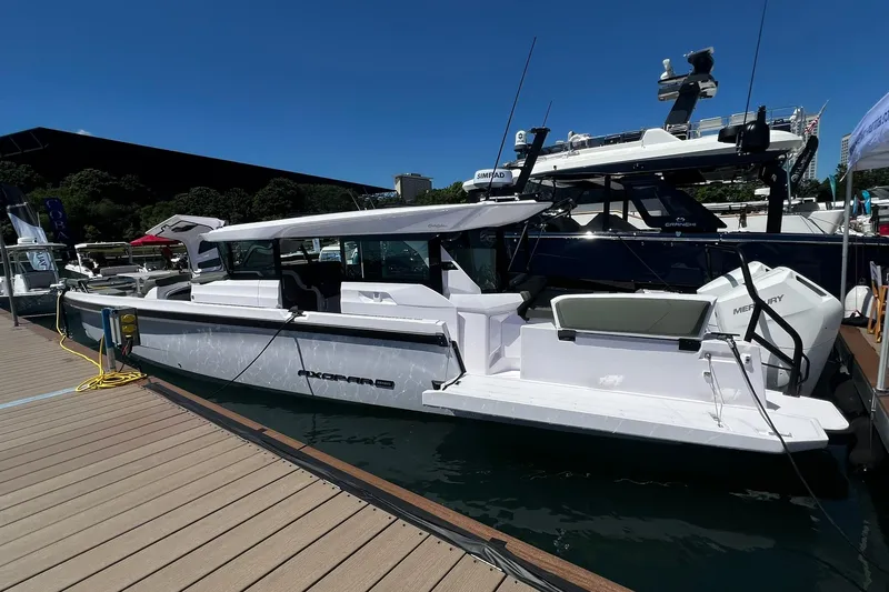 Slide: The Image of 2027 Axopar 38 Cross Cabin boat docked at marina under clear blue sky. - 2