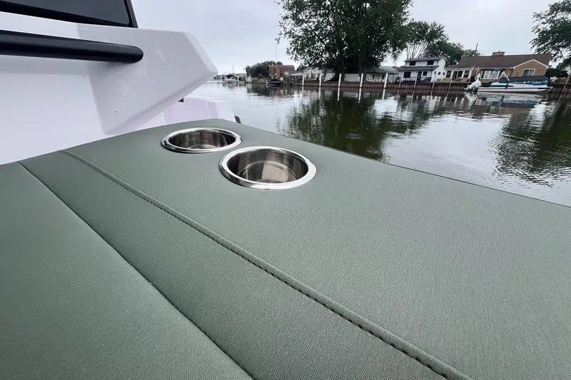 Slide: The Image of 2027 Axopar 38 Cross Cabin with green upholstery and cup holders, docked by waterfront homes. - 46