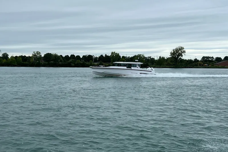 The Image of 2027 Axopar 38 Cross Cabin cruising on a calm river under cloudy skies. - 0