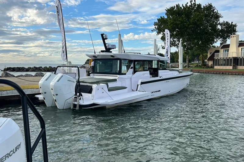 Slide: The Image of 2027 Axopar 38 Cross Cabin boat docked, featuring twin Mercury engines, under a partly cloudy sky. - 50