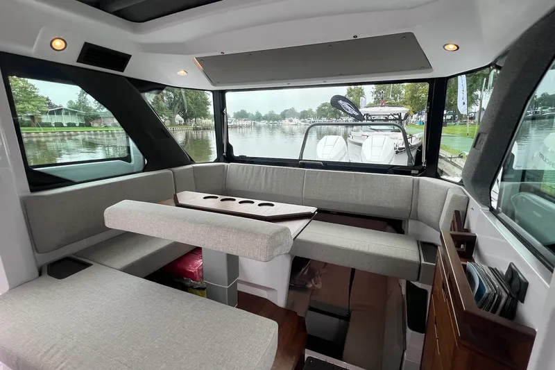 Slide: The Image of Interior of 2027 Axopar 38 Cross Cabin with seating and table, docked by a lake. - 11