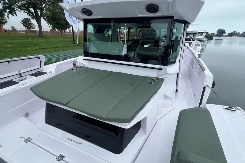 Slide: The Image of 2027 Axopar 38 Cross Cabin boat with green seating, docked by a serene lake. - 42