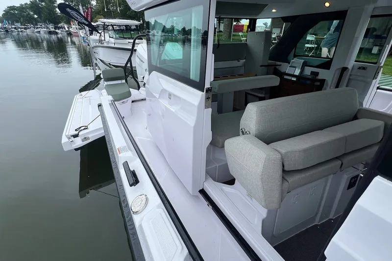 Slide: The Image of 2027 Axopar 38 Cross Cabin boat interior with seating, docked by the water. - 35