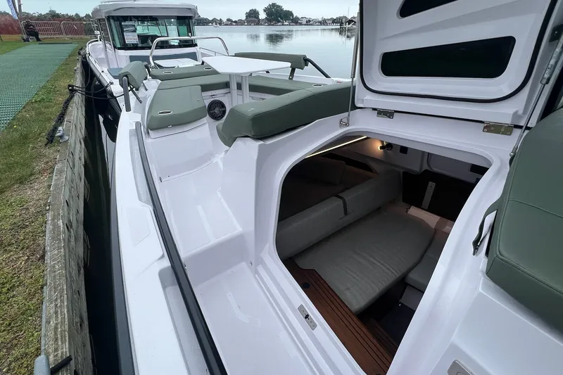 Slide: The Image of 2027 Axopar 38 Cross Cabin boat with open cabin and seating area by the water. - 34