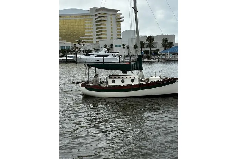 Slide: The Image of 1982 Falmouth Cutter 22 sailboat docked near modern buildings and palm trees. - 11