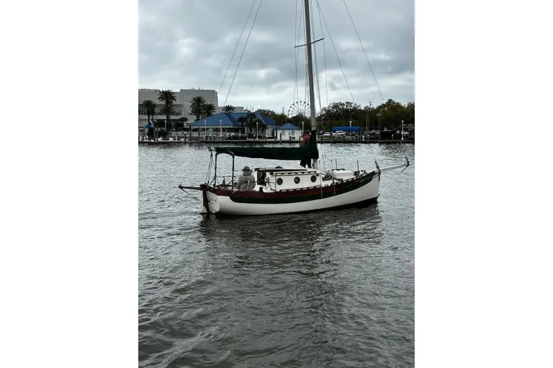 Slide: The Image of 1982 Falmouth Cutter 22 sailboat on calm waters, overcast sky, marina background. - 12