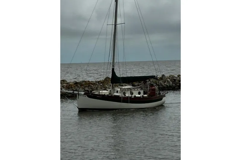 Slide: The Image of 1982 Falmouth Cutter 22 sailboat on calm waters near rocky shoreline. - 14