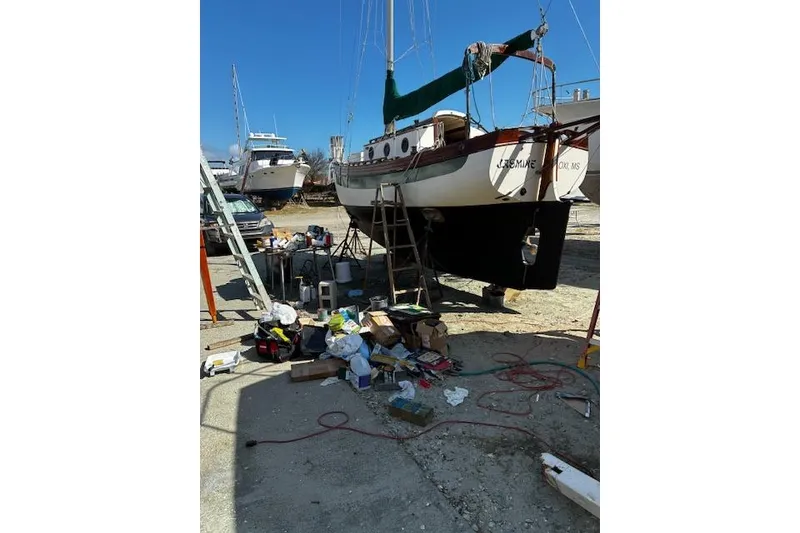Slide: The Image of 1982 Falmouth Cutter 22 sailboat under maintenance with tools and equipment nearby. - 2