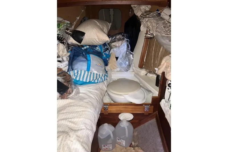Slide: The Image of Interior of a cluttered 1982 Falmouth Cutter 22 sailboat cabin with various items stored. - 25