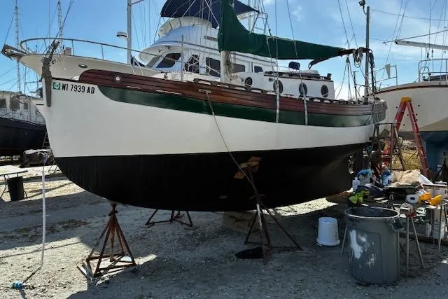 Slide: The Image of 1982 Falmouth Cutter 22 sailboat on stands, undergoing maintenance in a boatyard. - 4