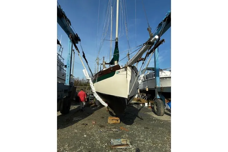 Slide: The Image of 1982 Falmouth Cutter 22 sailboat in dry dock, supported by cranes. - 9