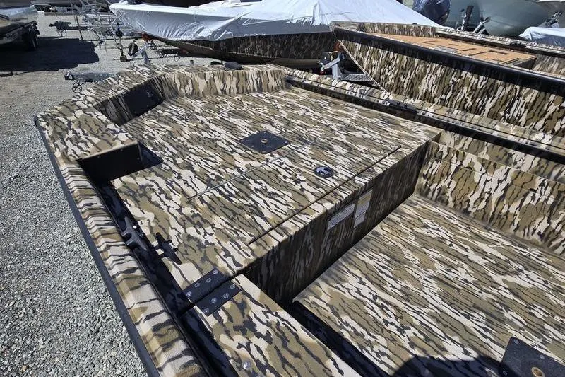 Slide: The Image of Camouflage-patterned 2025 Avid 16 Commander boat on gravel lot. - 6