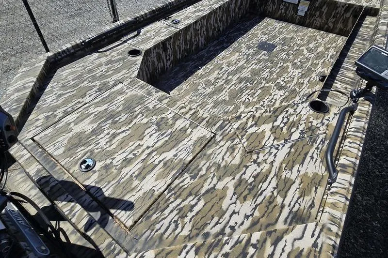 Slide: The Image of Camouflage interior of 2025 Avid 16 Commander boat, featuring storage compartments and cup holders. - 7