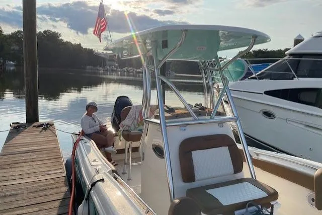 Slide: The Image of 2021 Pioneer 222 Islander boat docked, with people relaxing onboard, American flag waving. - 8