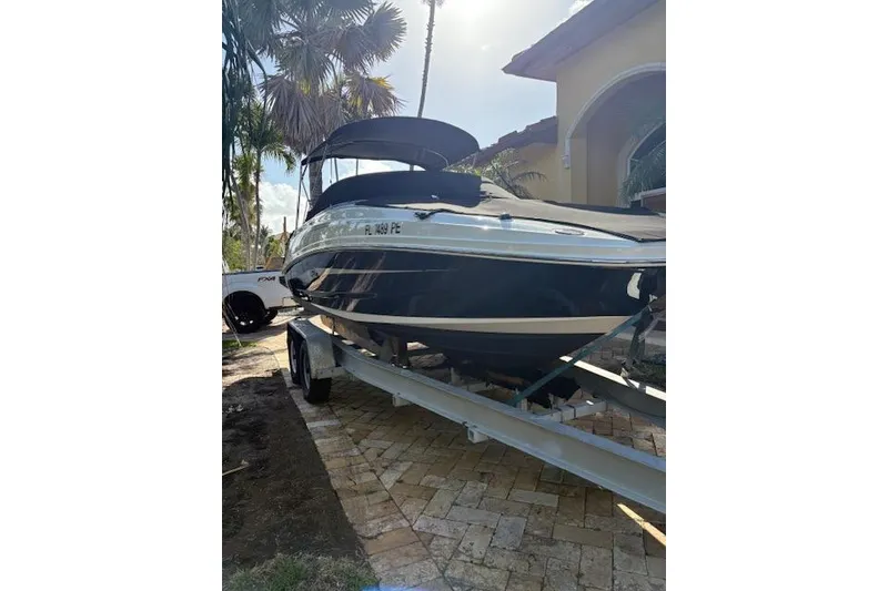 The Image of 2011 Sea Ray 220 Sundeck boat on lift, clear sky, palm trees in background. - 0