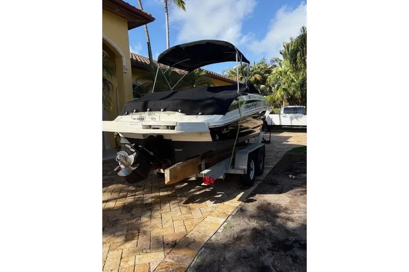 Slide: The Image of 2011 Sea Ray 220 Sundeck boat on a lift at a marina, surrounded by palm trees. - 17