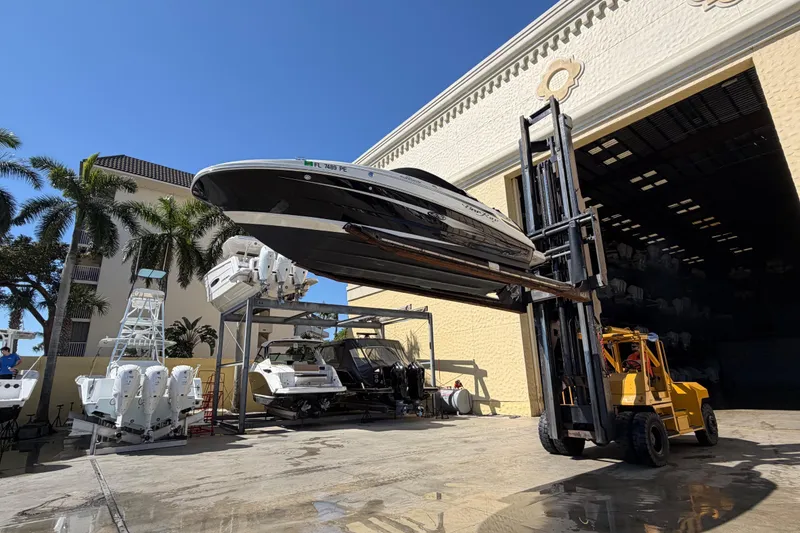 Slide: The Image of 2011 Sea Ray 220 Sundeck lifted by forklift near storage facility. - 21