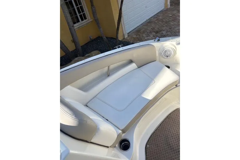 Slide: The Image of 2011 Sea Ray 220 Sundeck boat docked, featuring seating and steering wheel under a sunny sky. - 8