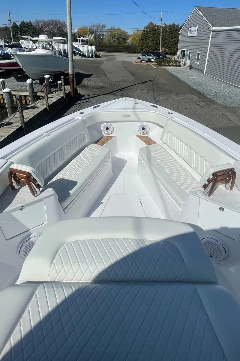 Slide: The Image of 2023 Jupiter 40 boat with white seating and wooden accents in a marina. - 15