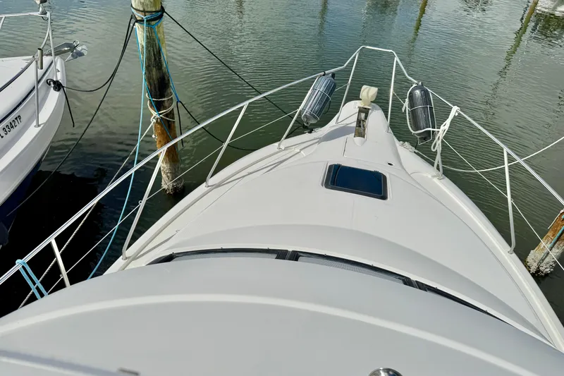 Slide: The Image of 2000 Silverton 322 Motor Yacht docked, view from bow, with water and pilings. - 16