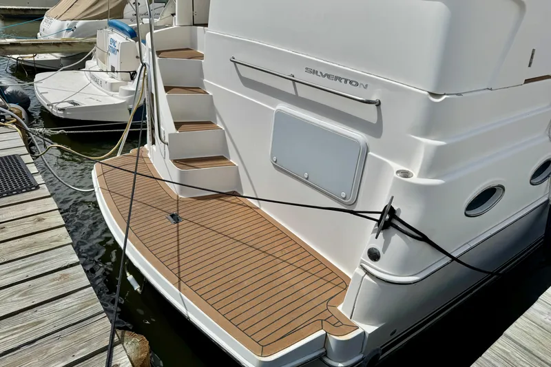 Slide: The Image of 2000 Silverton 322 Motor Yacht docked, showcasing rear deck and steps. - 2