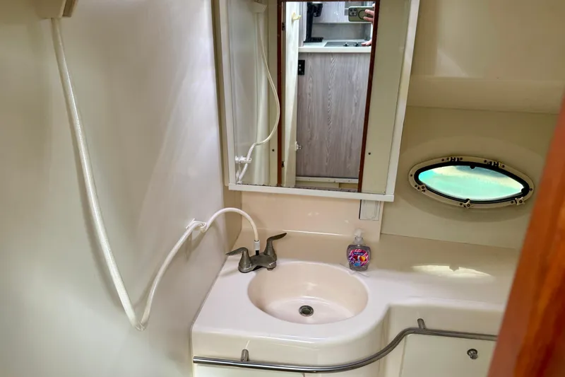 Slide: The Image of Bathroom interior of 2000 Silverton 322 Motor Yacht with sink, mirror, and porthole window. - 30