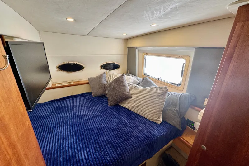 Slide: The Image of Cozy bedroom in 2000 Silverton 322 Motor Yacht with blue bedding and porthole windows. - 32
