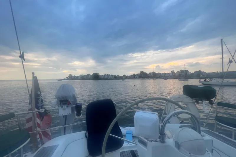 Slide: The Image of Sailboat Beneteau 393 (2001) on calm waters at sunset, with coastal town view. - 2