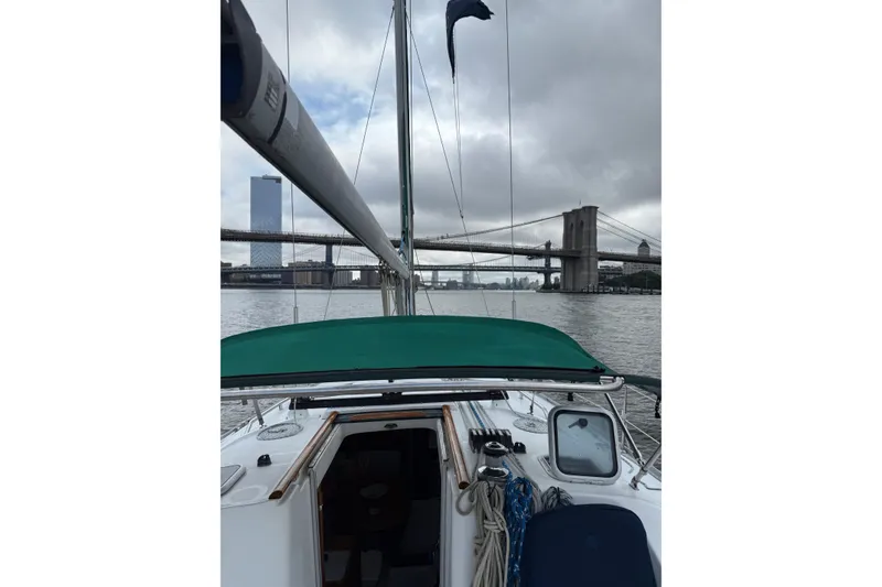 Slide: The Image of Sailing on a 2001 Beneteau 393 yacht under a cloudy sky near a bridge. - 5