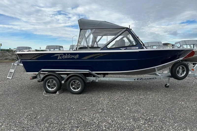 The Image of 2026 Weldcraft 200 Rebel boat on trailer, parked outdoors under cloudy sky. - 1