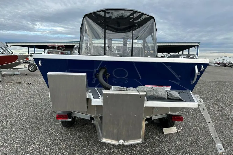 Slide: The Image of 2026 Weldcraft 200 Rebel boat, rear view, parked on gravel lot under cloudy sky. - 4