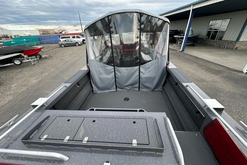 Slide: The Image of 2026 Weldcraft 210 Revolution boat with covered seating area, parked outdoors. - 6