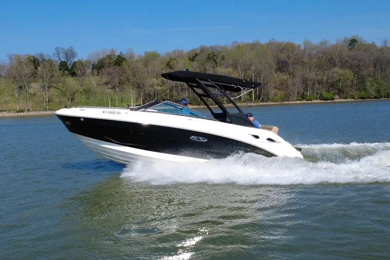 Slide: The Image of 2023 Sea Ray SDX 250 boat cruising on a lake with scenic forest backdrop. - 16