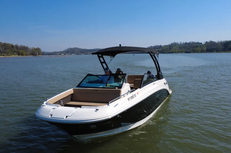 Slide: The Image of 2023 Sea Ray SDX 250 boat cruising on a serene lake under a clear blue sky. - 18
