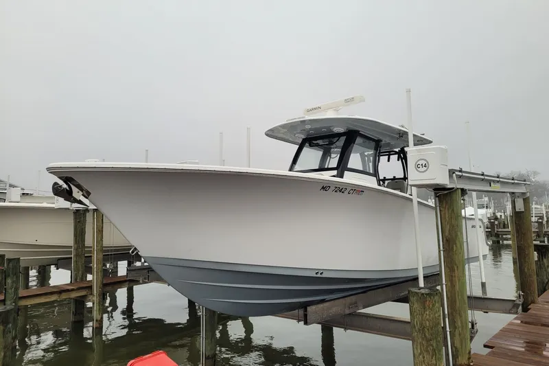 The Image of 2022 Sportsman Open 302 Center Console boat docked on a lift in a marina. - 1