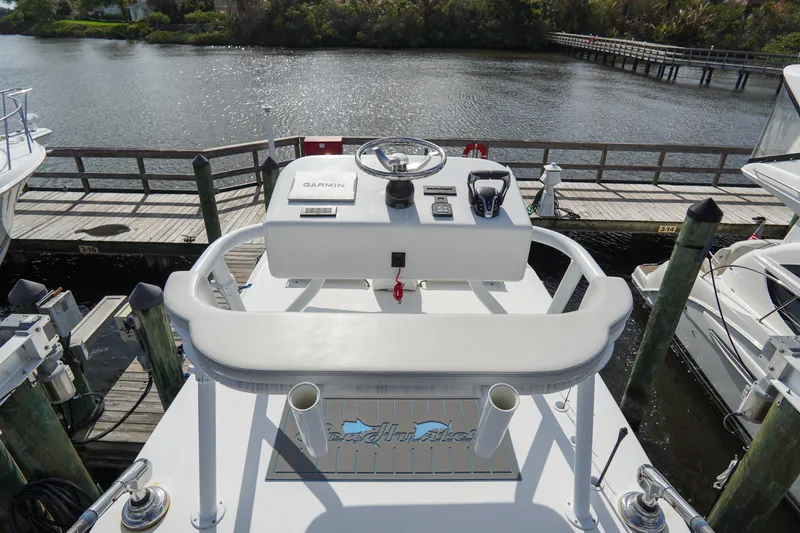 Slide: The Image of 2022 SeaHunter 41 CTS boat helm with Garmin navigation, docked by a scenic waterfront. - 29