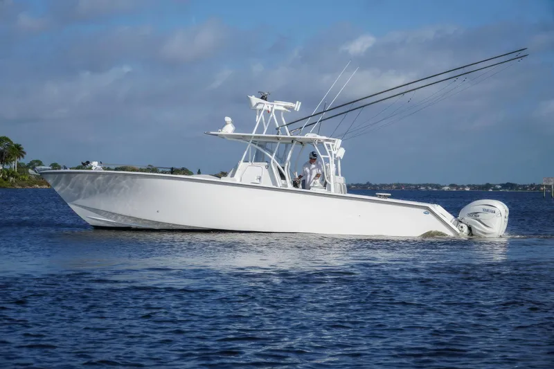 Slide: The Image of 2022 SeaHunter 41 CTS boat on calm water with fishing rods and Yamaha engines. - 5
