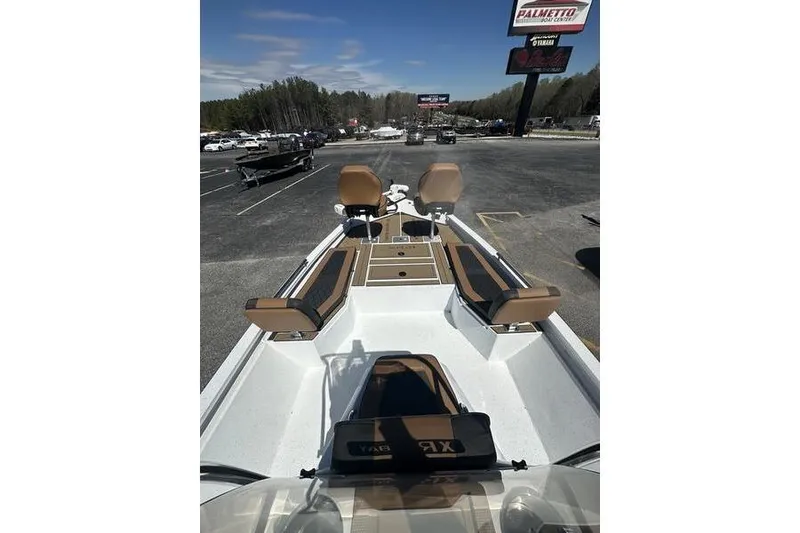 Slide: The Image of 2026 Xpress XR21 Bay boat interior with tan seating and deck, parked outdoors. - 10