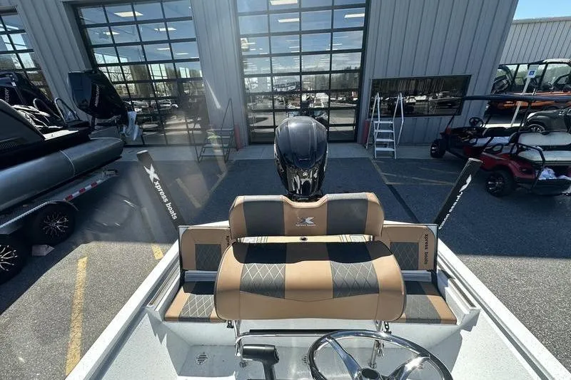 Slide: The Image of 2026 Xpress XR21 Bay boat interior with tan and black seating, parked outside dealership. - 21