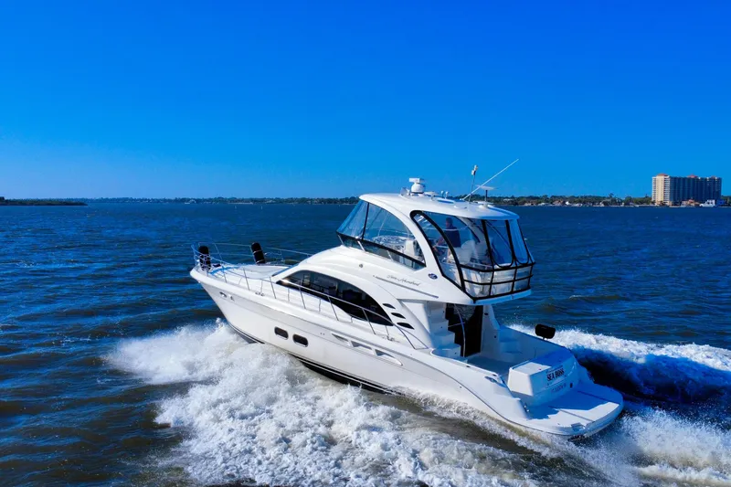 Slide: The Image of 2005 Sea Ray 500 Sedan Bridge yacht cruising on open water under clear blue sky. - 1