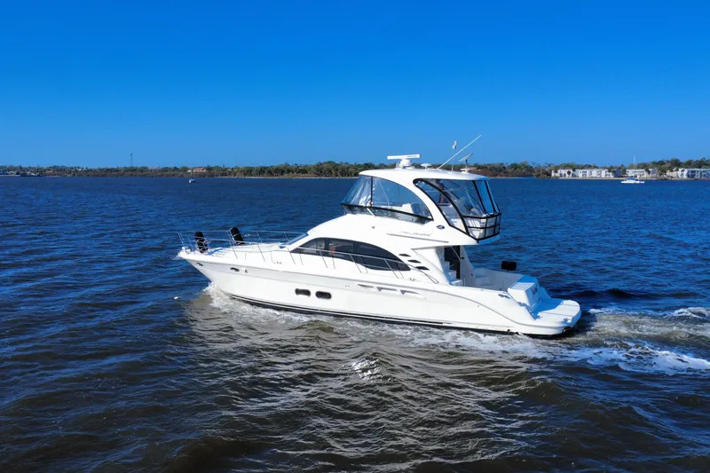 Slide: The Image of 2005 Sea Ray 500 Sedan Bridge yacht cruising on open water under clear blue sky. - 12