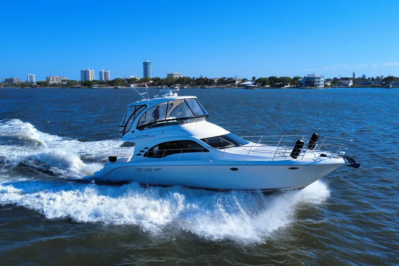 Slide: The Image of 2005 Sea Ray 500 Sedan Bridge yacht cruising on open water, city skyline in background. - 2