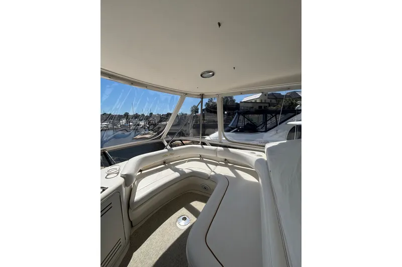 Slide: The Image of 1999 Sea Ray 480 Sedan Bridge interior with marina view, featuring spacious seating and clear windows. - 18