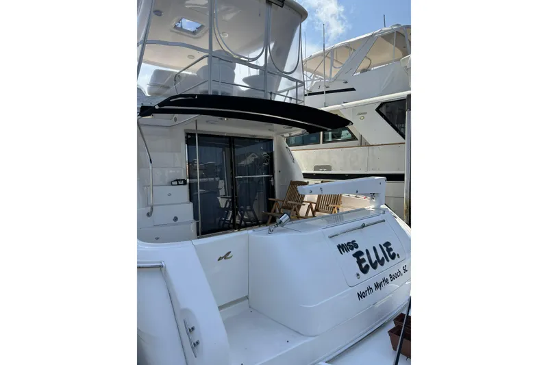 Slide: The Image of 1999 Sea Ray 480 Sedan Bridge yacht docked, featuring spacious deck and seating area. - 7