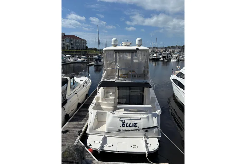 Slide: The Image of 1999 Sea Ray 480 Sedan Bridge yacht docked in a marina under a blue sky. - 6