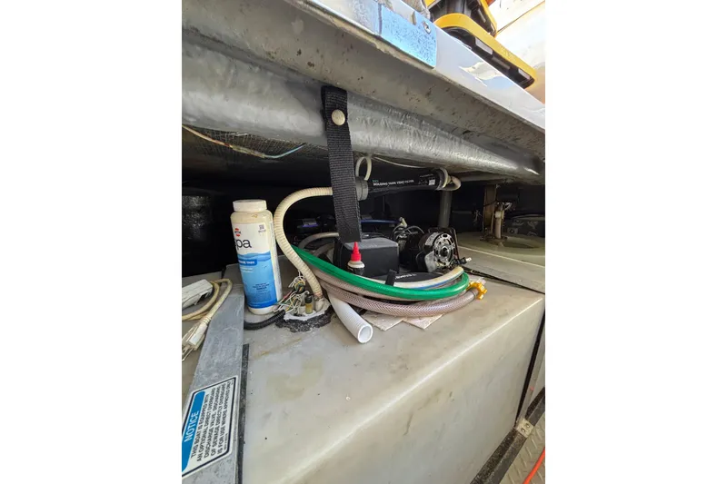 Slide: The Image of Engine compartment of a 1999 Sea Ray 480 Sedan Bridge with hoses and maintenance supplies. - 96