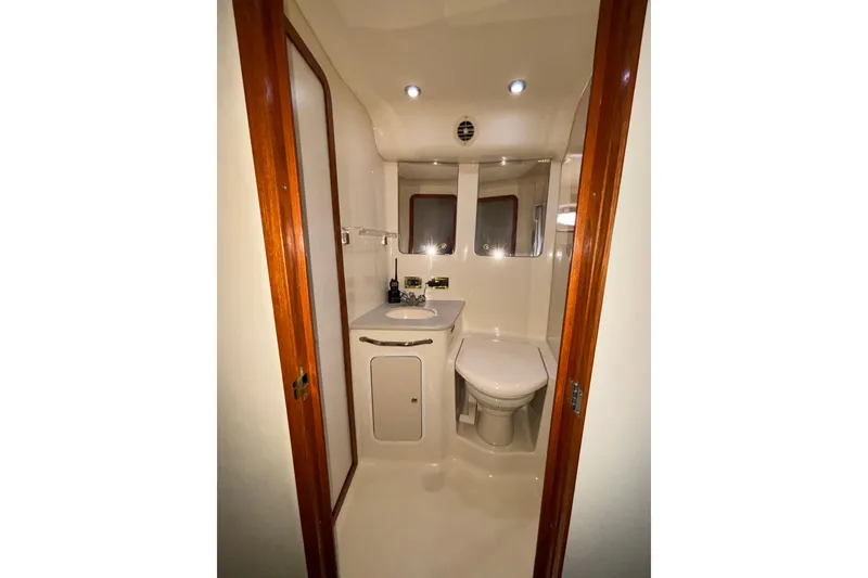 Slide: The Image of 1999 Sea Ray 480 Sedan Bridge bathroom with sink, toilet, and wooden accents. - 57