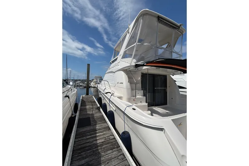 Slide: The Image of 1999 Sea Ray 480 Sedan Bridge yacht docked at marina under clear blue sky. - 10