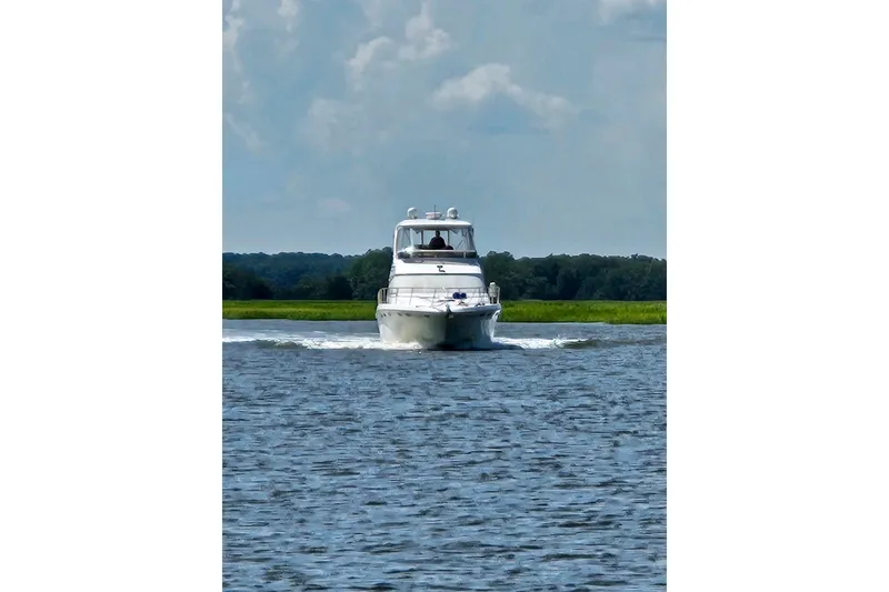 Slide: The Image of 1999 Sea Ray 480 Sedan Bridge cruising on a calm river under a cloudy sky. - 3