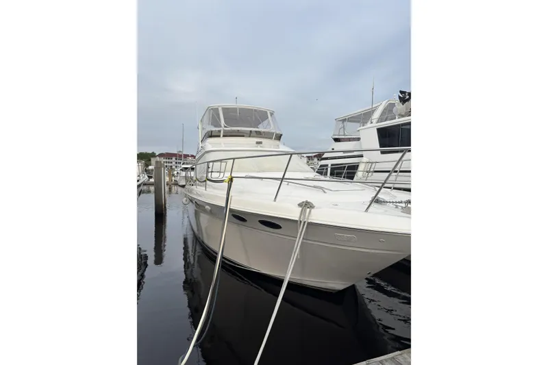 Slide: The Image of 1999 Sea Ray 480 Sedan Bridge yacht docked at marina, showcasing sleek design and spacious deck. - 1